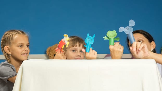 Mom and daughters show a performance in a fingered self-made puppet theater