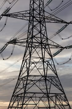 Electricity pylons or transmission towers carrying high voltage power lines and overhead cables above land as part of the national grid network supplying power to peoples homes and businesses