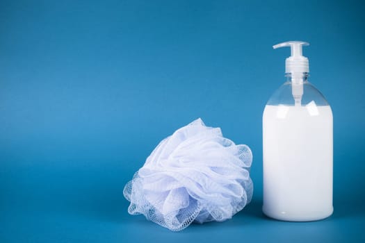 White shower gel and bath sponge are on blue background.