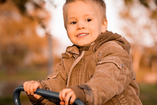 The young blond hair boy in autumn colors at autumn outdoor.