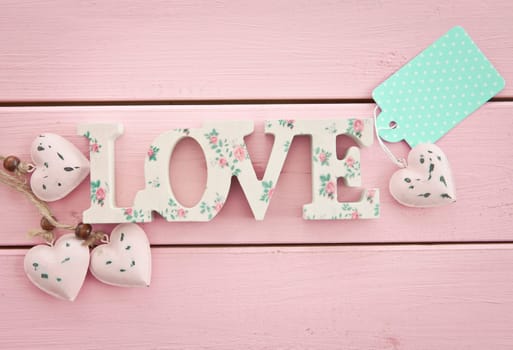 LOVE on pink wooden background with small hearts