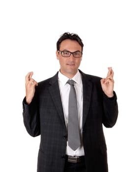 A young business man sitting in a dark gray suit and tie with his crossed .finger, hoping everything is going fine, isolated for white background.