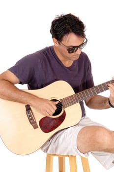 A handsome young man sitting in casual clothing playing his guitar.and singing for himself, isolated for white background.