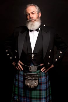 close up of senior man with grey hair and full beard, wearing scotting kilt on dark background