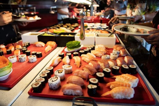 Buffett dinner. Hands picking up Sushi and fish specialties in buffett dinner at luxury hotel. Food concept.