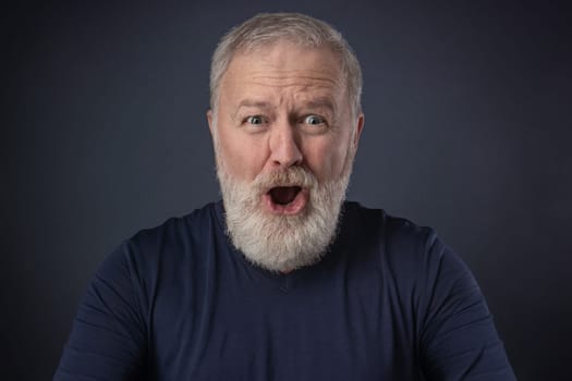 An elderly man with a gray beard with a very surprised mimic