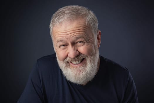 Elderly man with a beard posing with a sly, fake mime
