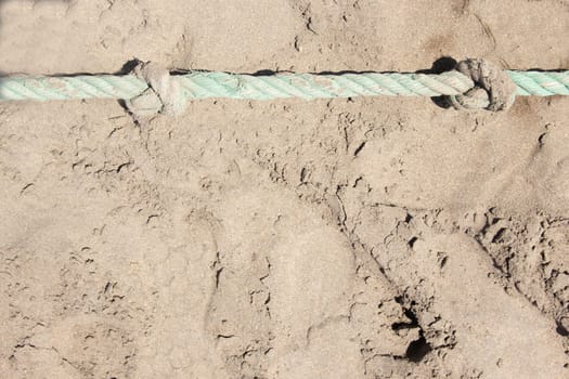 Close-up of rope knots on sand beach. Safety concept coast.