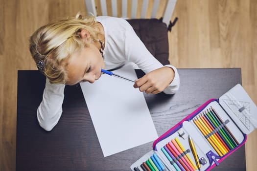 Cute girl comtemplation about her homework for elementary school at home.