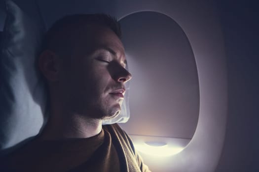 Traveling by airplane. Young passenger sleeping during flight.