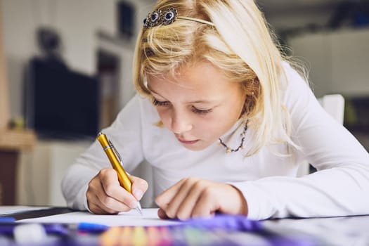 Cute girl writing her homework for elementary school at home.