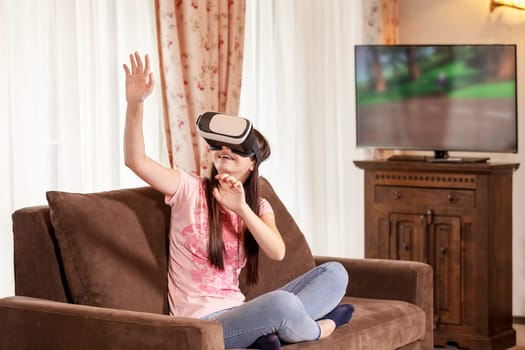 Happy teenager girl having fun with virtual reality glasses at home. People and new technology concept.