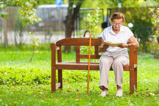 Elderly woman sitting and relaxing on a bench outdoors in park