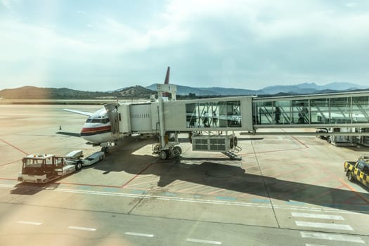 Airplane Boarding on the airport before departure. Passenger carrying the hand luggage, walking the airplane boarding corridor.