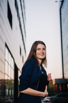 Successful businesswoman stands on the background of buildings and holding tablet computer. City business woman working.