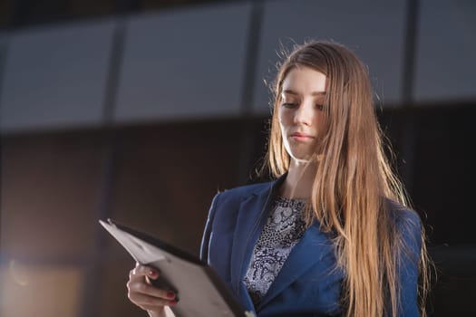 Successful businessman standing on background buildings looking at the folder charts of sales. City business woman working.