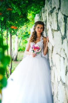 Beautiful young bride standing on a stone wall background