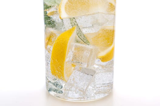 Drink of ice, the lobules of fresh juicy yellow lemon and crystal clear water in a glass.