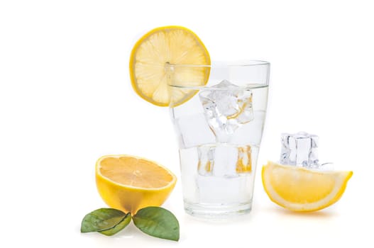 Water, lemon and ice cubes in a glass. Lemon slices and flax next to a glass.