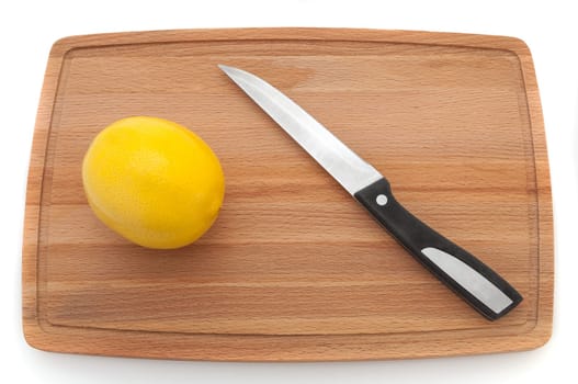 bright fresh lemon with a knife on a wooden board.