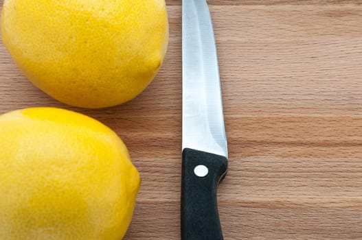 lemons and knife close-up on a cutting board.