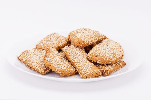 On a white plate, on a white background biscuits to sesame.