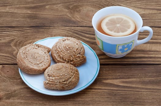 A cup of fragrant tea with lemon and biscuits with sesame.