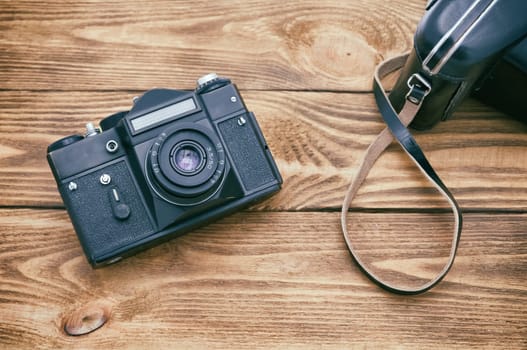 An old camera on a table made of textured boards.