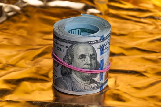 Convolving notes one hundred US dollars on a bright gold background.