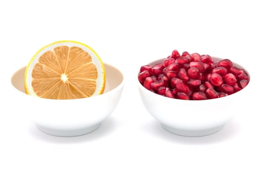 Yellow lemon and pomegranate in cups on a white background.