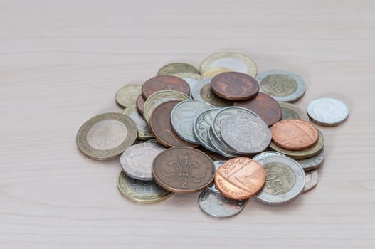 A handful of coins of different countries, dignity and size are scattered on the table.