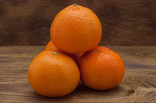 Four bright orange ripe mandarines laying a slide on a table.