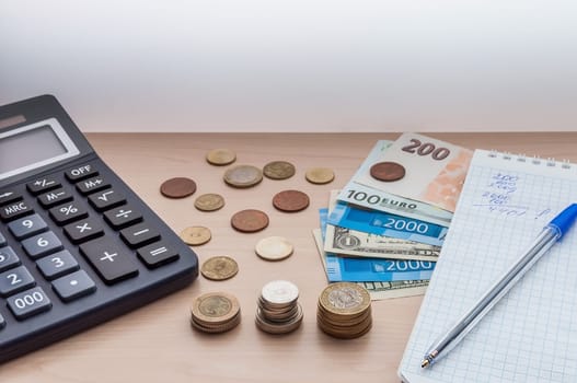Calculator, coins, banknotes, money, a notebook a pen on the table