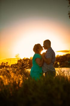 Romantic couple standing and kissing on background summer lake sunset