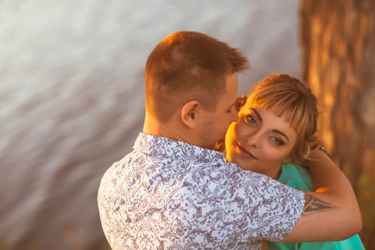 Romantic couple standing and kissing on background summer meadow sunset