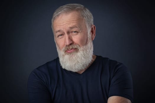 Old man with gray beard posing a despise grimace in studio
