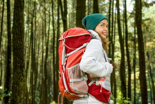Smiling asian traveler woman with backpack explore the forest