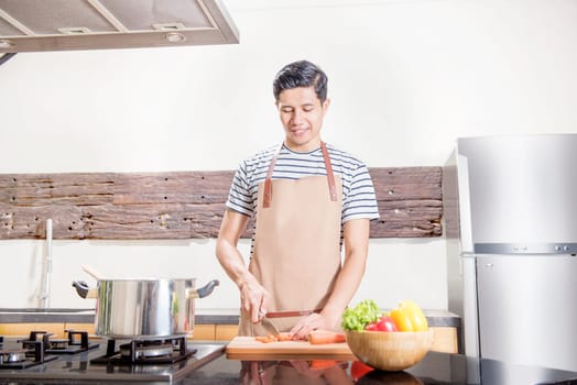Handsome asian man slice the carrot for cooking on the kitchen