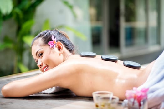 Young asian woman relaxing with hot stone massage on the spa salon