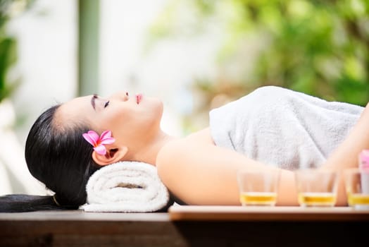 Happy asian woman lying on massage table on spa salon