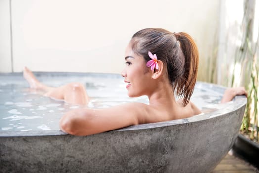 Smiling asian woman relaxing on the bathtub