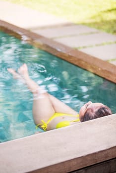 Rear view of asian woman with swimwear relaxing in swimming pool