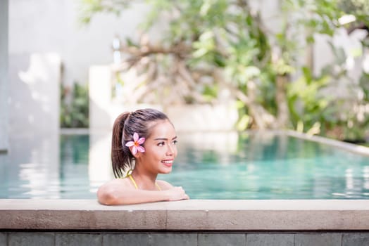 Smiling asian woman relaxing on the poolside.