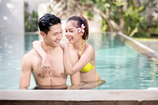 Portrait of asian couple enjoy relaxing time on the swimming pool
