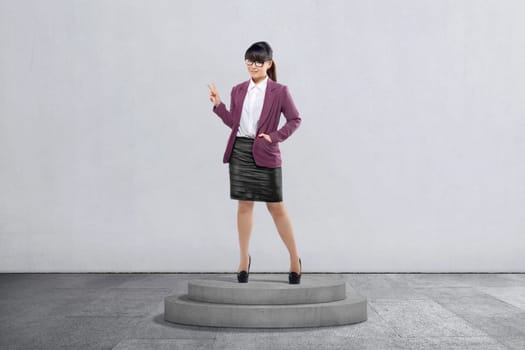 Attractive asian businesswoman standing with peace sign over gray wall background