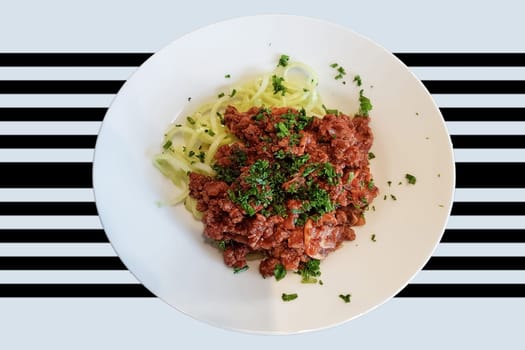 Healthy low carb food on white plate, lunch with snake cucumber in spaghetti strips cut above beef tartare with tomato sauce.