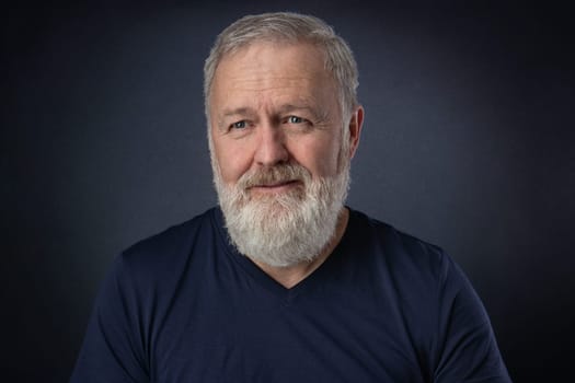 Happy 60 year old man with gray beard posing in the studio
