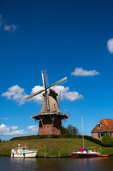 Dokkum, Friesland, The Netherlands - August 17, 2018  Boats on canal and windmill on fortifications of historic town Dokkum, Friesland, The Netherlands.