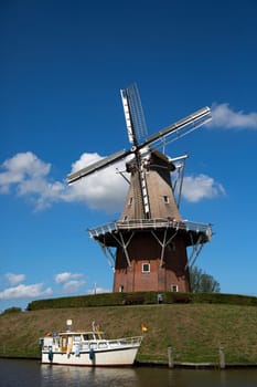 Dokkum, Friesland, The Netherlands - August 17, 2018  Boats on canal and windmill on fortifications of historic town Dokkum, Friesland, The Netherlands.