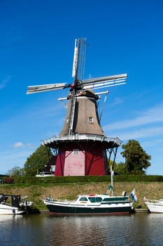 Dokkum, Friesland, The Netherlands - August 17, 2018  Boats on canal and windmill on fortifications of historic town Dokkum, Friesland, The Netherlands.